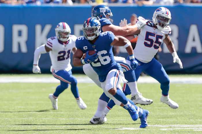 New York Giants running back Saquon Barkley (26) carries the ball as Buffalo Bills defensive end Jerry Hughes (55) pursues during the first half at MetLife Stadium.